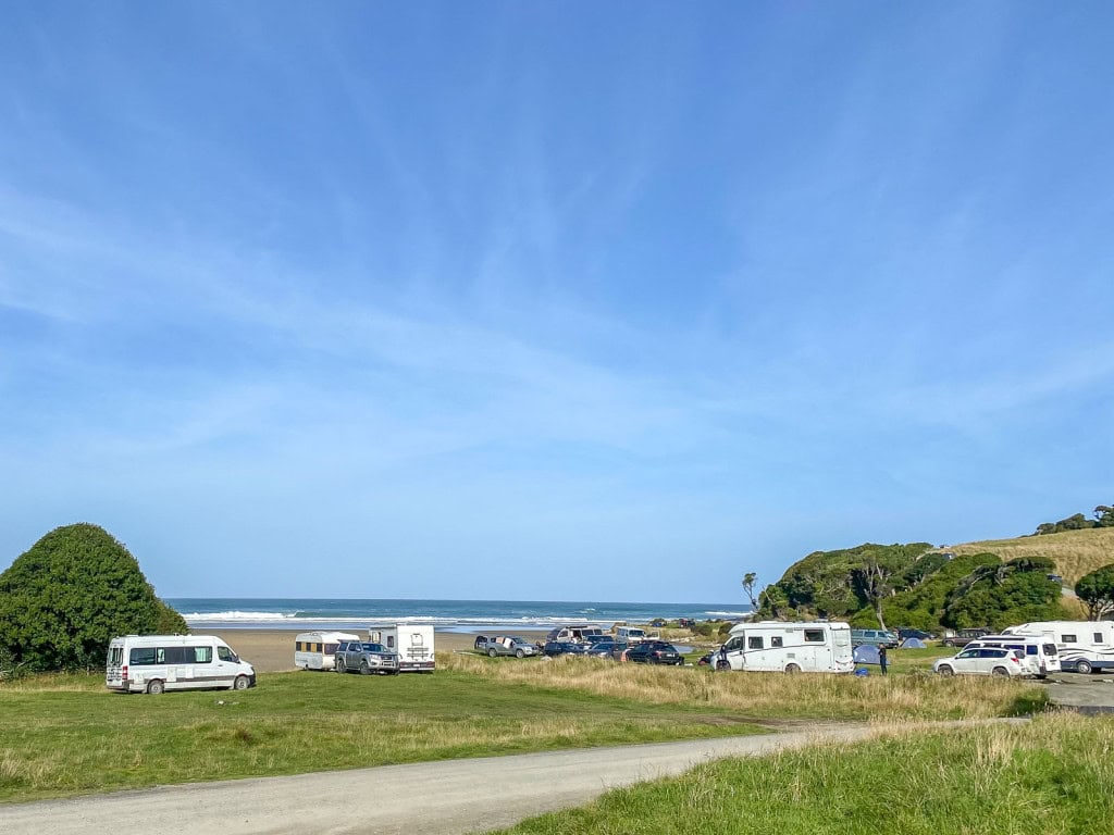Campervans parked at the beachfront Purakaunui Bay DOC Campsite in the Catlins on the South Island, New Zealand.