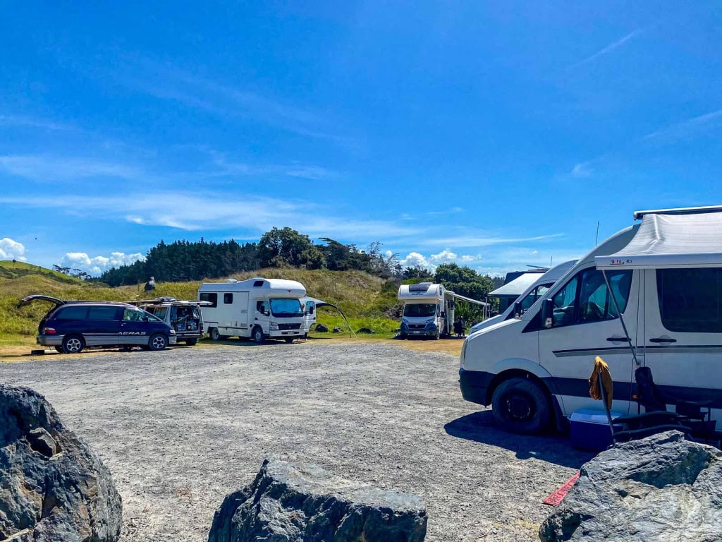 Campervans parked at a gravel campervan site near Te Arai Beach on the North Island of New Zealand.