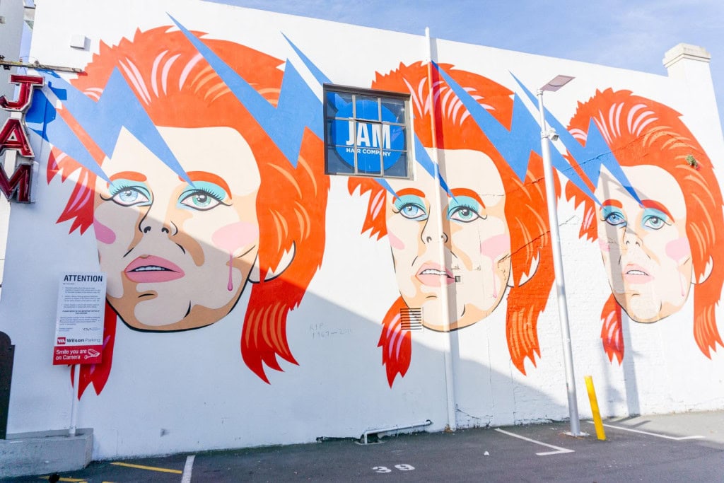 The David Bowie street art mural in Wellington, with 3 identical paintings of David Bowie's face on the side of a building.