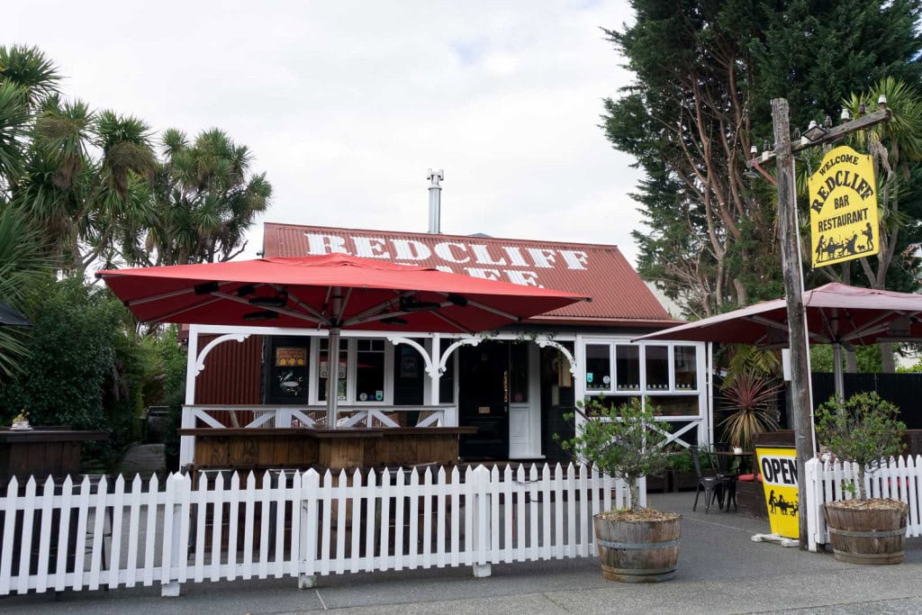 Redcliff Cafe in Te Anau, with a white picket fence and a red roof.