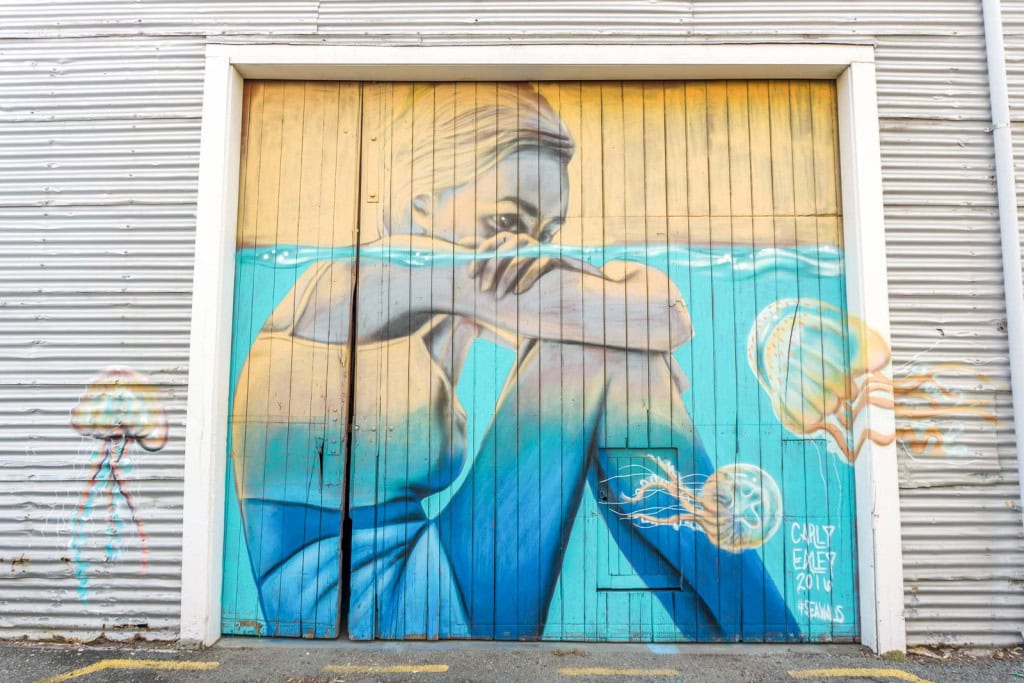 A mural in Napier by Carly Ealey depicting a woman sitting in water surrounded by jellyfish.