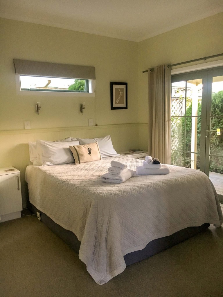A cosy room with a made-up bed at Clive Colonial Cottages in Hawke's Bay.