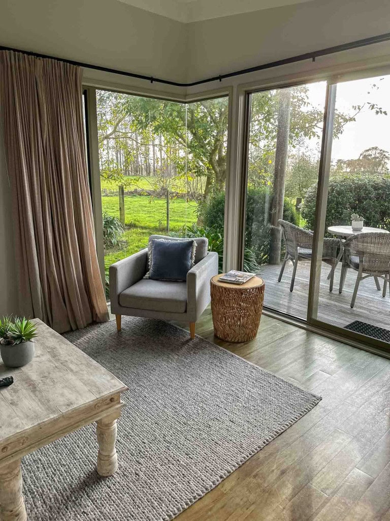A living room with a garden view at Te Awanga Cottages in Hawke's Bay.