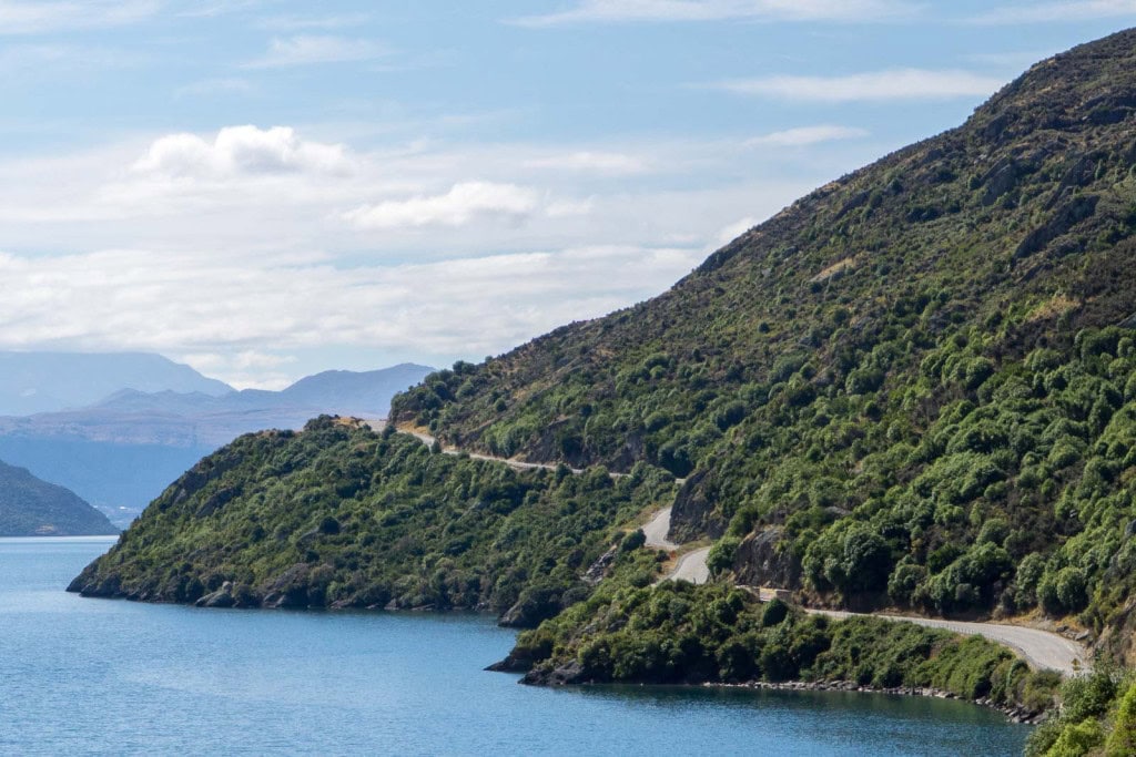 A closeup shot of the Devil's Staircase road between Queenstown and Te Anau, with Lake Wakatipu on one side and bush-covered hills on the other.
