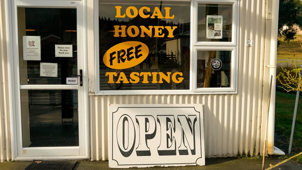 The entrance to the Garston Hunny Shop with a sign on the window for "Local honey free tasting."