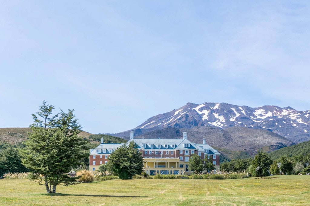 The historic Chateau Tongariro Hotel in Whakapapa Village with snow-dusted mountains in the background.
