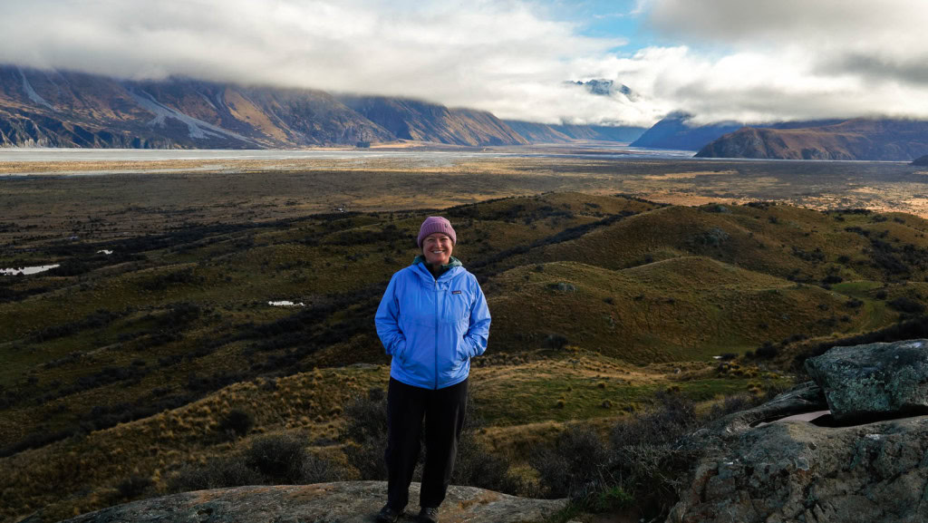 Jac from Weekend Path at the Summit of Mount Sunday (Edoras), with views of the valley and mountains in the background.