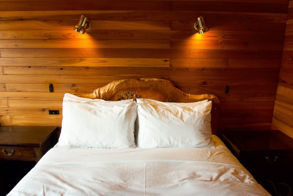 A bed in a cosy room with wood panelling at Powderhorn Chateau in Ohakune.
