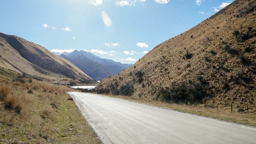 Moke Lake Road, with Lake Kirkpatrick and snow-capped mountains in the distance.